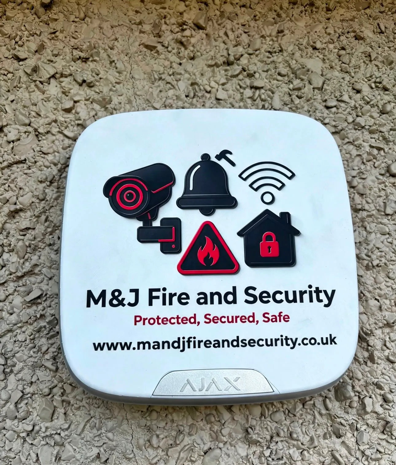 Ajax external sounder finished with M&J Fire and Security branding, fitted to a rendered wall.