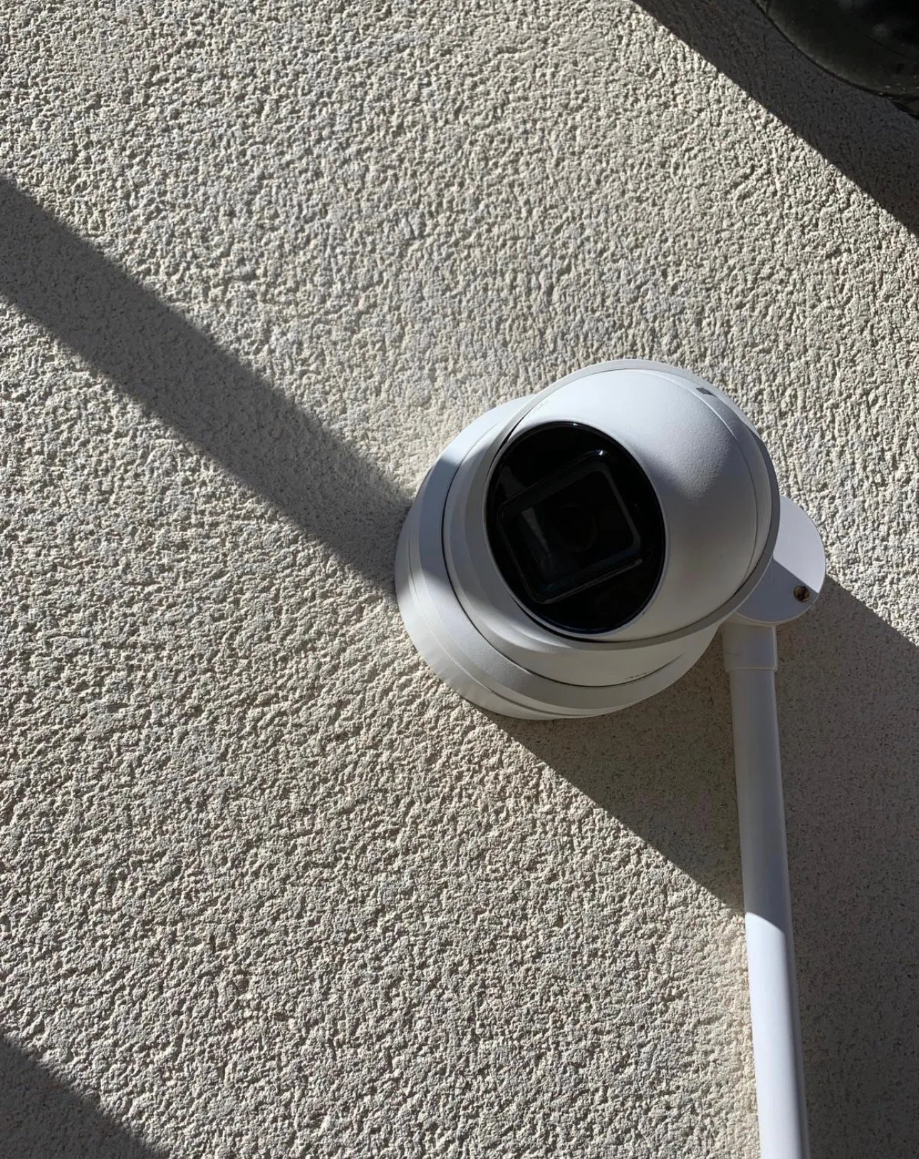 Close-up of white dome turret camera mounted on textured wall surface.