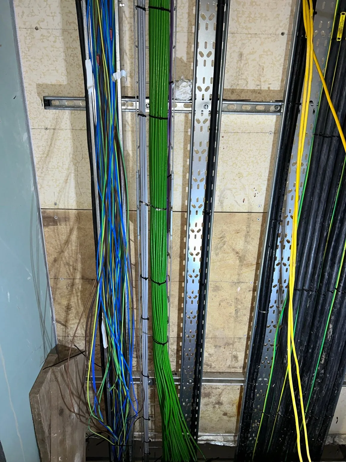 Colour-coded data and fibre cabling run neatly up a vertical cable riser between floors.